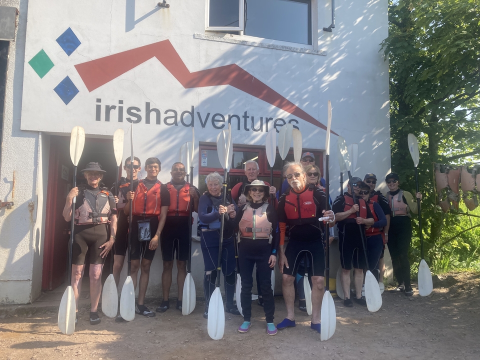 Group of people in front of a building marked 'Irish Adventures' with paddles.