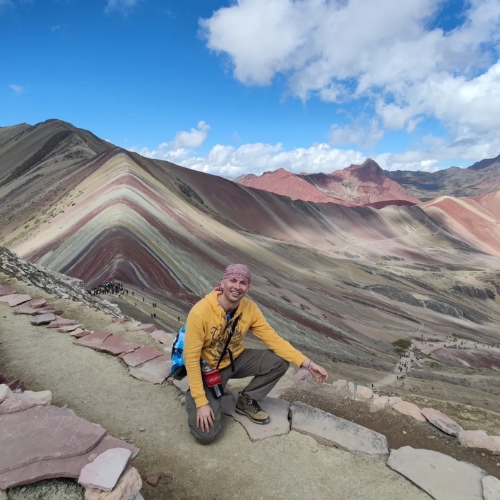 Personne posant devant les couches colorées de la Montagne Arc-en-ciel.