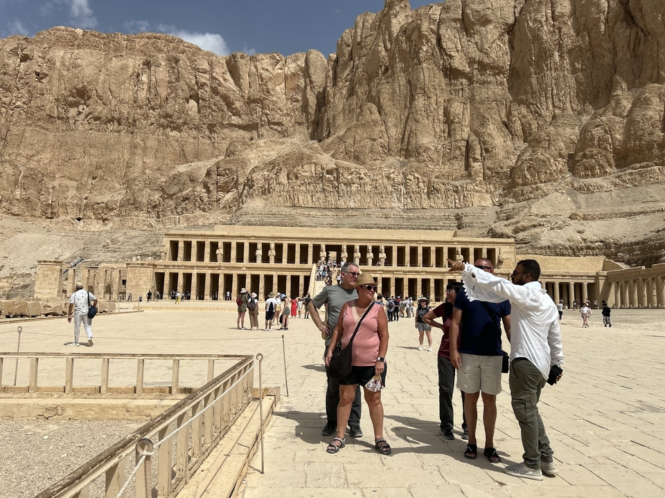 Un groupe de touristes et un guide debout devant un temple ancien.