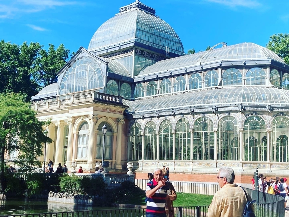 Palais de Cristal dans un parc avec des gens devant.