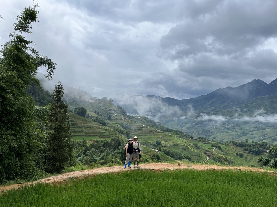 Deux personnes qui posent devant une vue panoramique de champs en terrasses et de montagnes.
