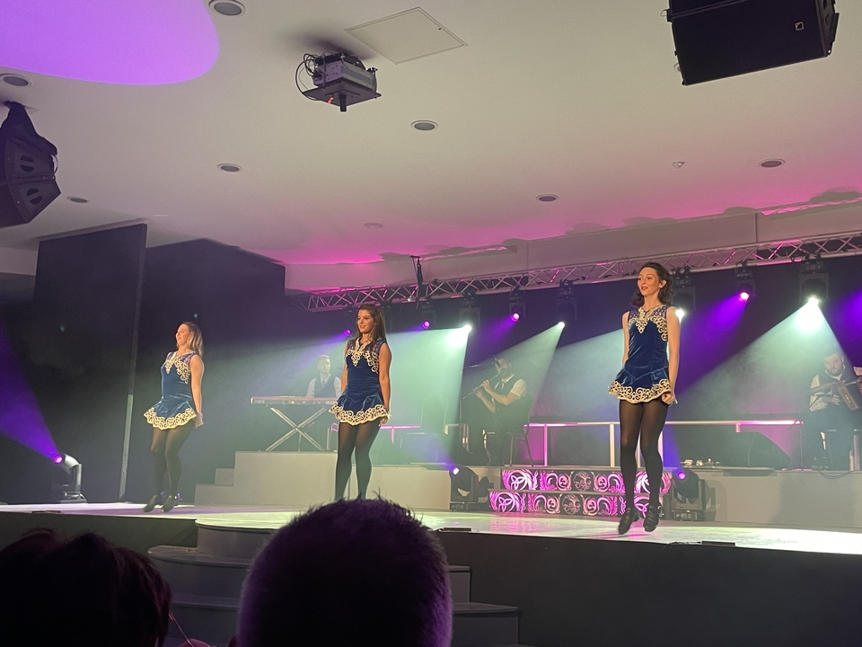 Dancers performing on stage with musicians in the background.