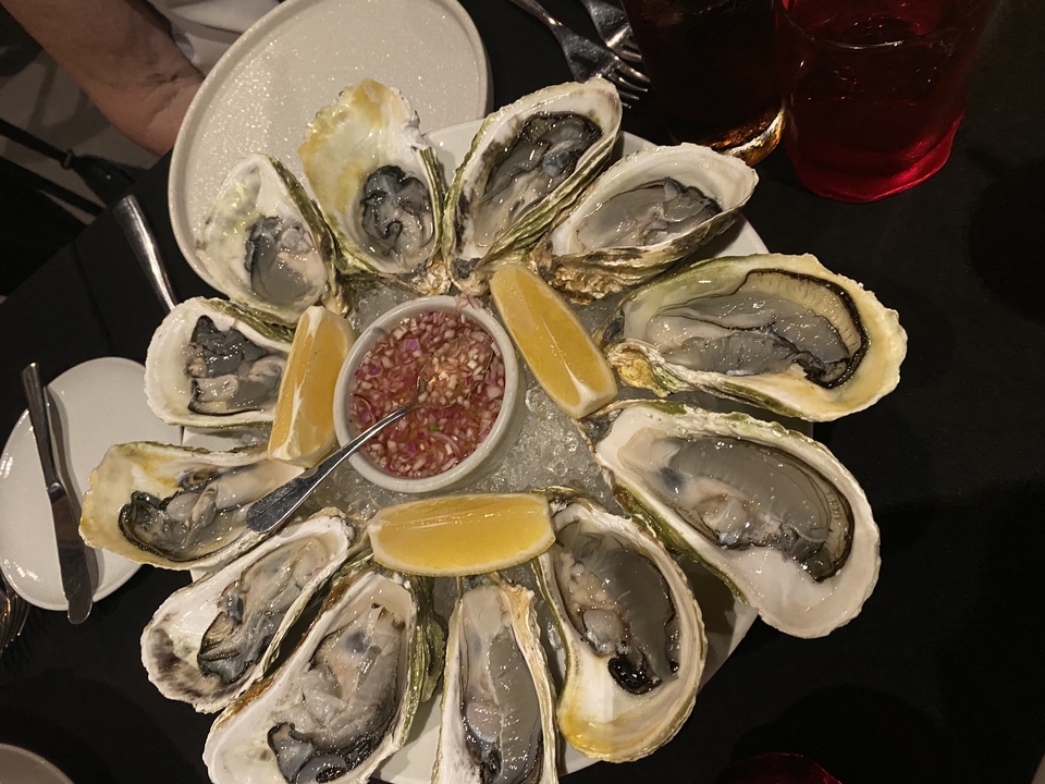 Assiette d'huîtres fraîches avec quartiers de citron et sauce.