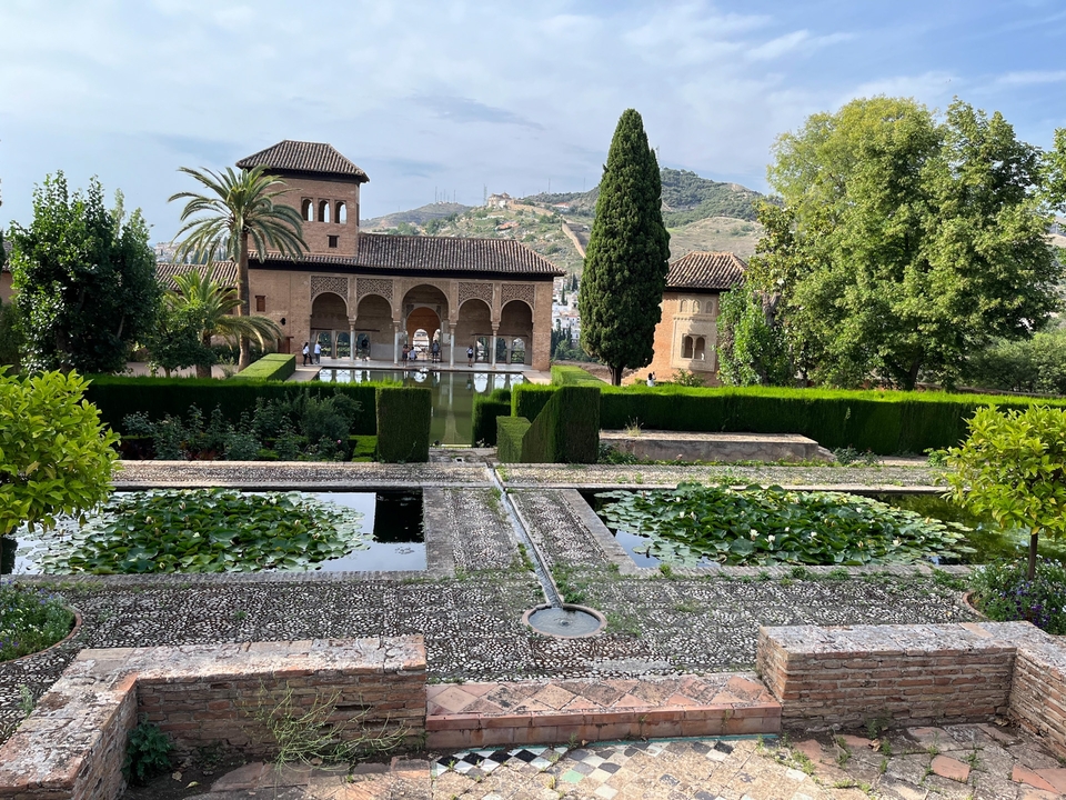 Historic palace gardens with pools and trimmed hedges.