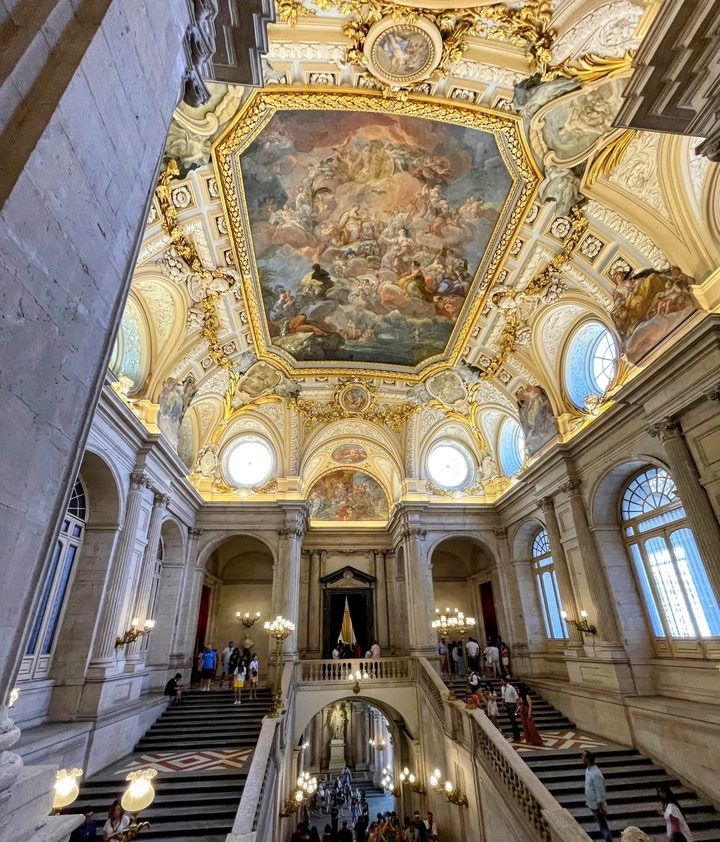 Opulent interior of a building with a painted ceiling and pillars.