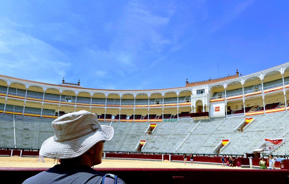 Bullring interior with spectators and a person wearing a hat.