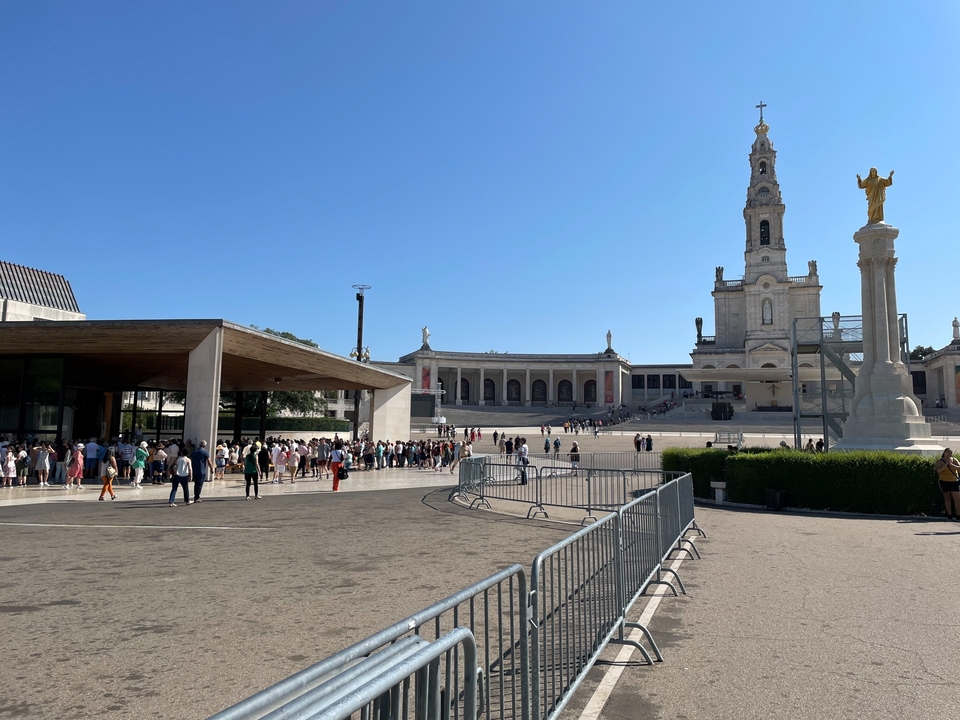 Plaza with a line of tourists and a cathedral in the background.