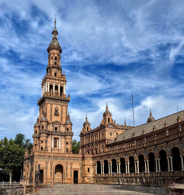 Ornate tower against a blue sky, part of a historic building.