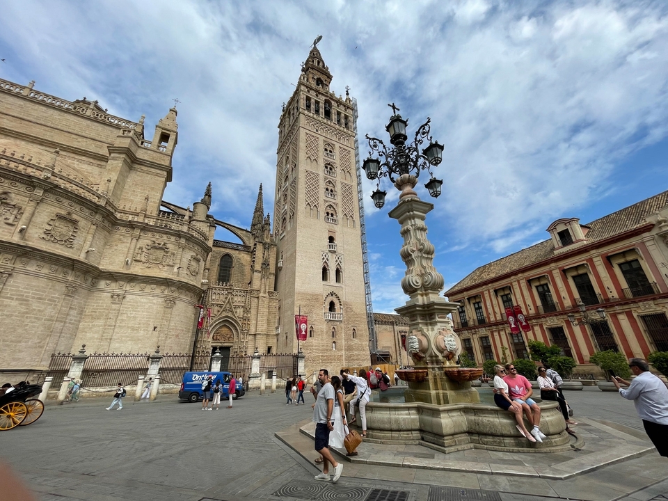 Historic cathedral with a bell tower and tourists.