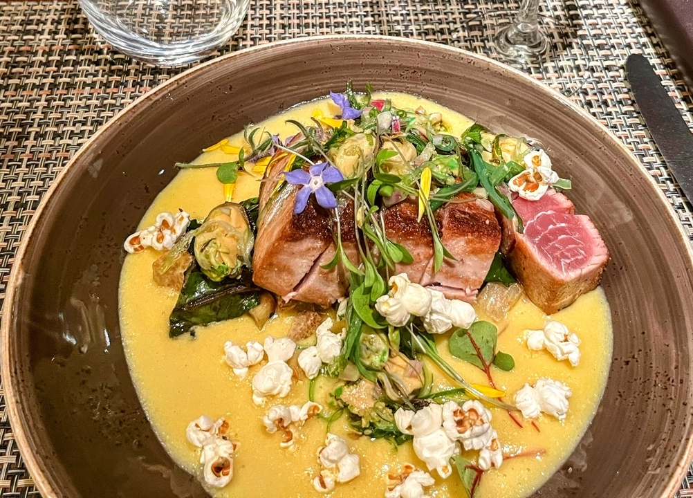 Gourmet dish with seafood, greens, and a light sauce.