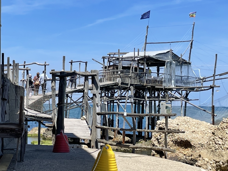 Structure de maison sur pilotis au-dessus de l'eau avec un ciel bleu clair.