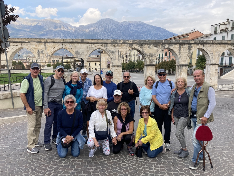 Groupe de personnes posant devant des arcs antiques.