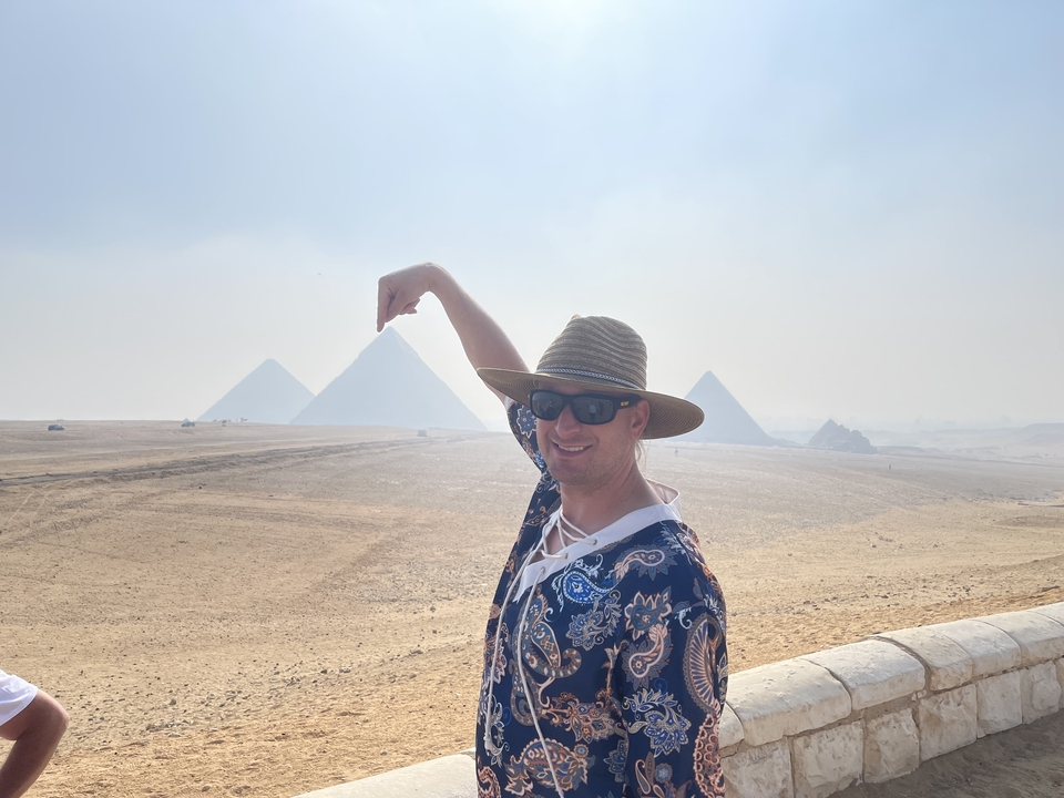 Person playfully posing in front of the pyramids.