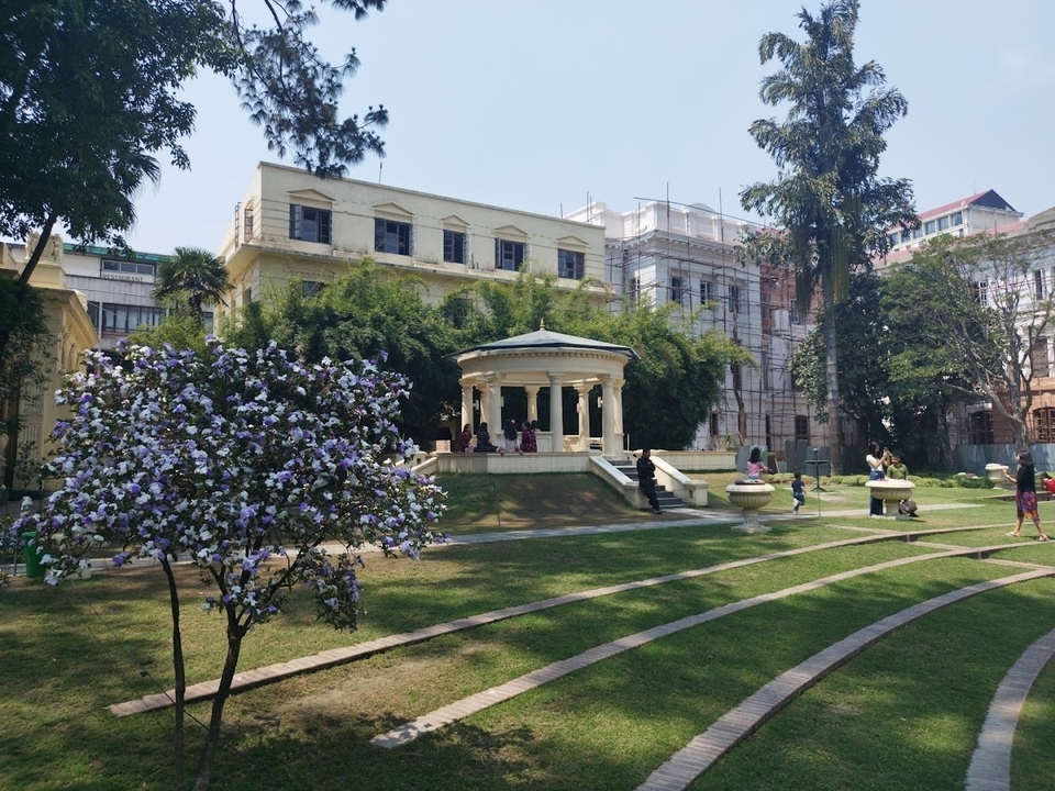 Un jardin avec un pavillon et des gens qui se détendent dans un parc.