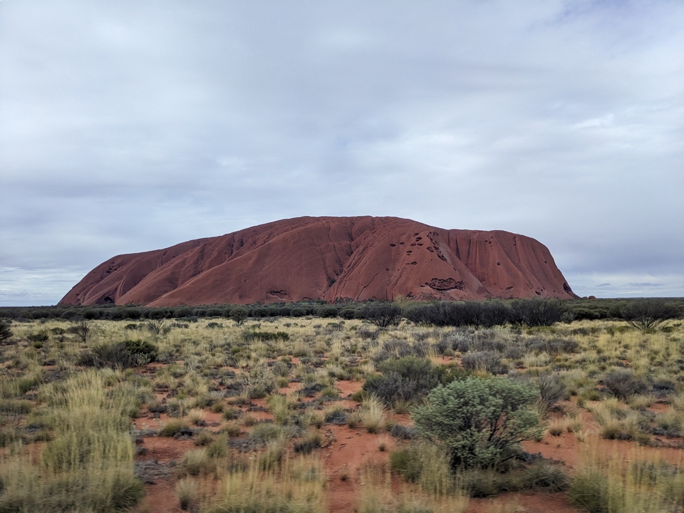 Vista lejana de Uluru con cielo nublado