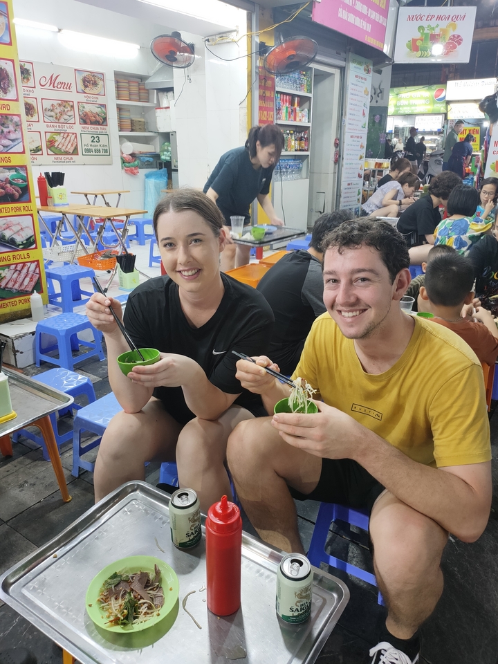 Deux personnes mangent des nouilles dans un restaurant de rue.