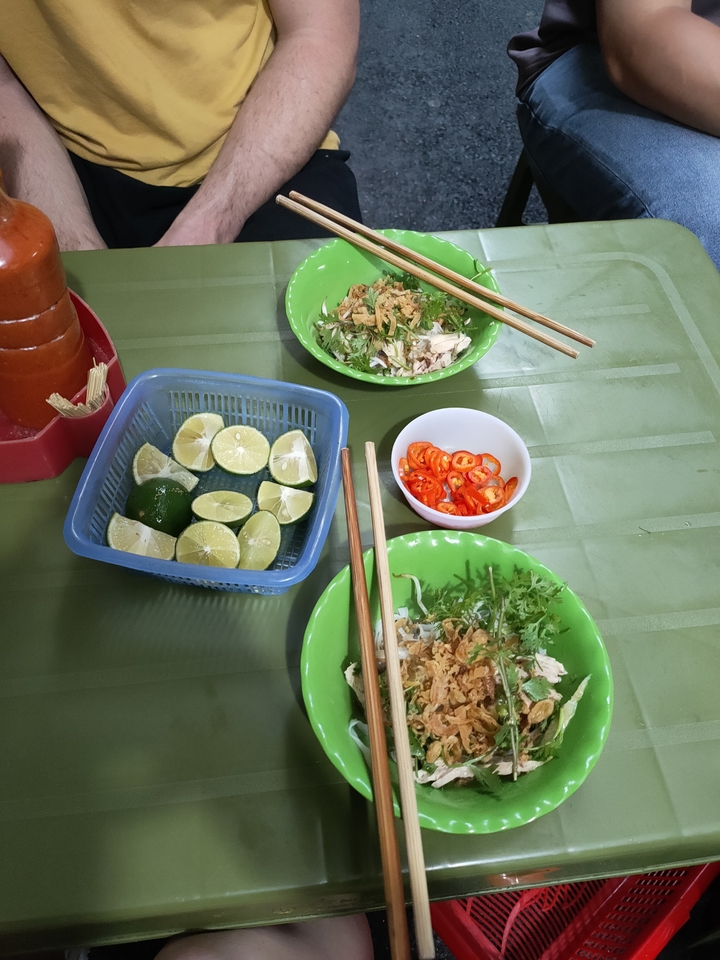 Plats vietnamiens avec citron vert, piment et légumes verts sur une table verte.