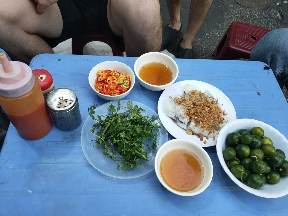 Nourriture vietnamienne avec du piment, des herbes et des sauces sur une table bleue.