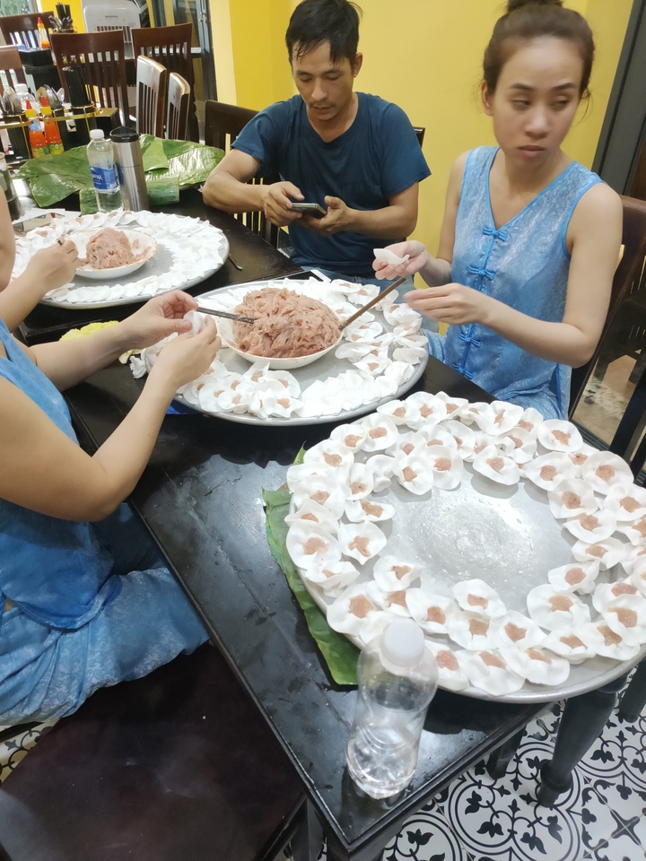 Des personnes préparant des boulettes traditionnelles autour d'une table.
