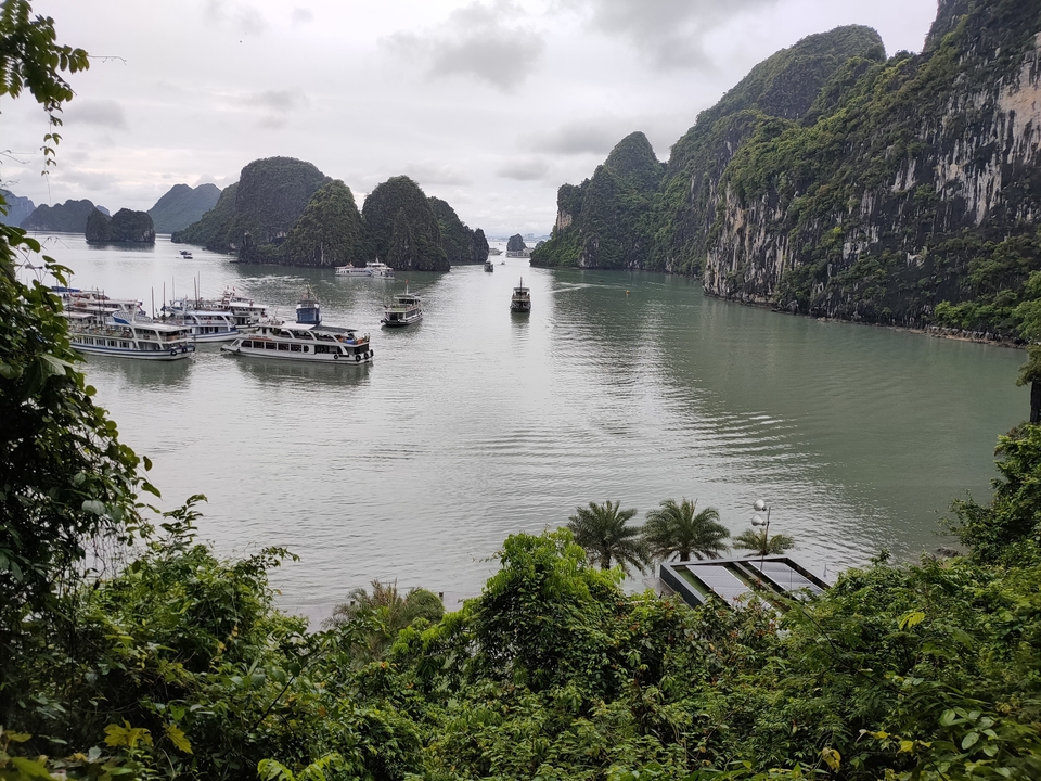 Vue panoramique de la baie d'Halong avec des bateaux et des îles calcaires.