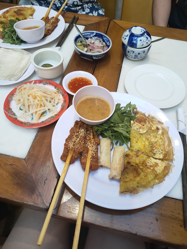 Assiette de nourriture vietnamienne avec des brochettes et des sauces.