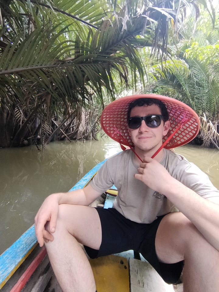 Personne portant un chapeau et des lunettes de soleil dans un canoë sur une voie navigable.