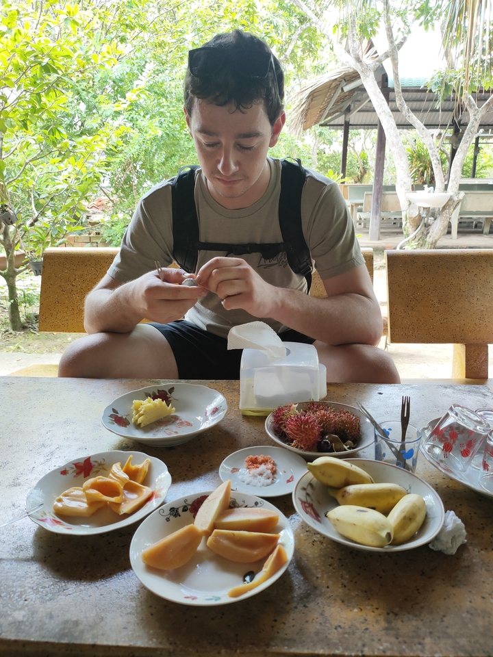 Personne assise à une table avec une variété de fruits et d'en-cas.