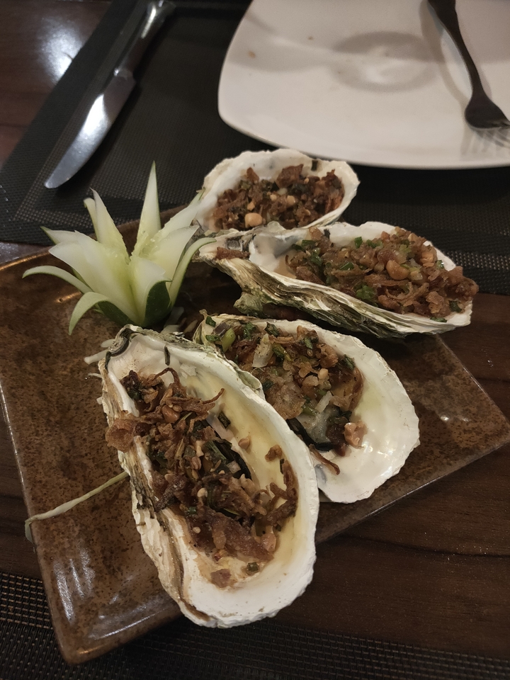 Huîtres grillées sur une assiette avec garniture.