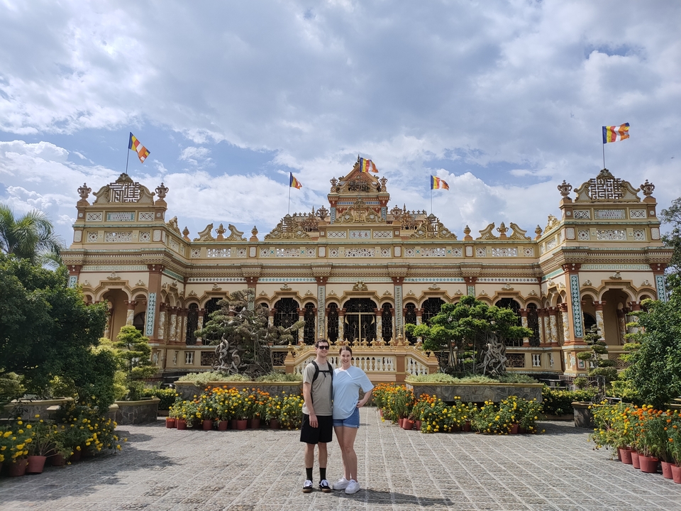 Deux personnes devant un temple orné de drapeaux.