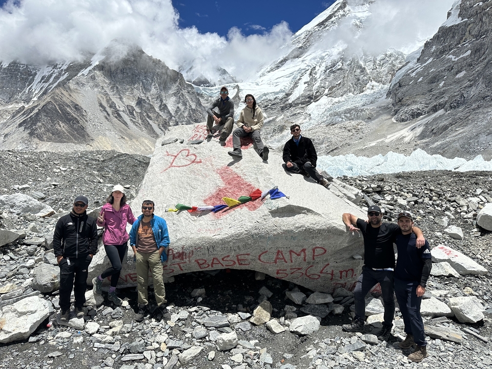Groupe de personnes posant près d'un rocher avec l'inscription Camp de base de l'Everest.