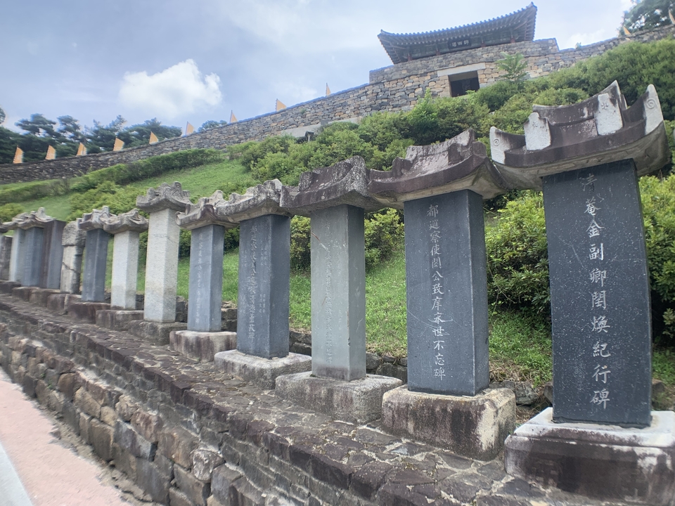 Tablettes de pierre avec inscriptions disposées dans un jardin paysager.