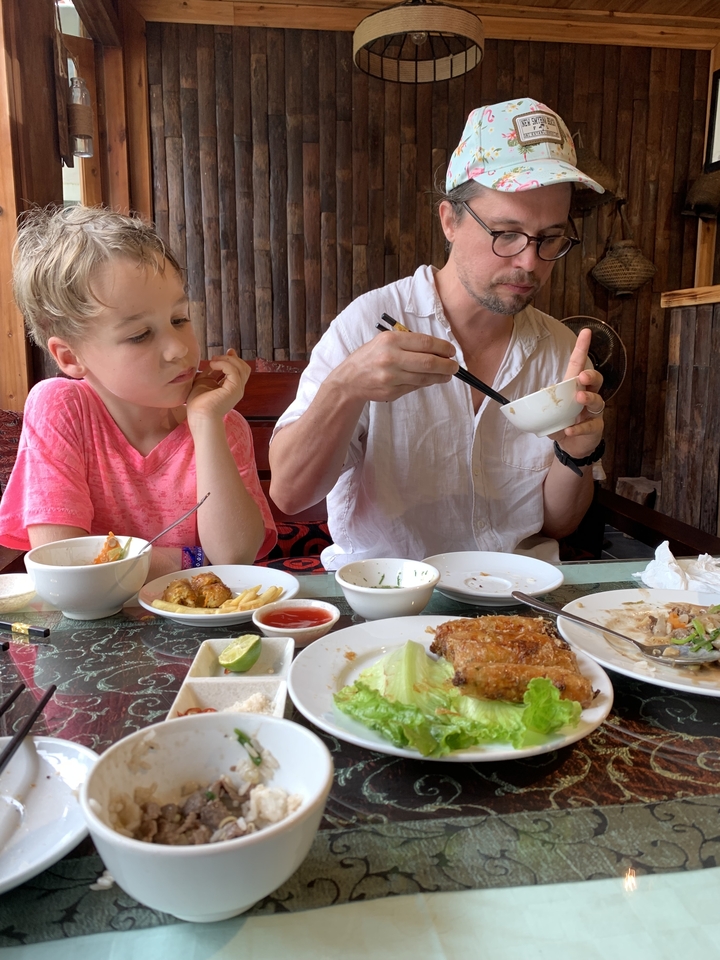 Un enfant et un adulte mangent à une table avec divers plats.