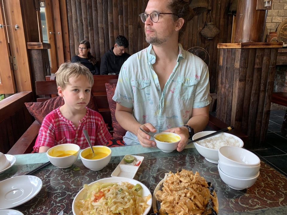 Un homme et un enfant assis à une table avec de la nourriture.