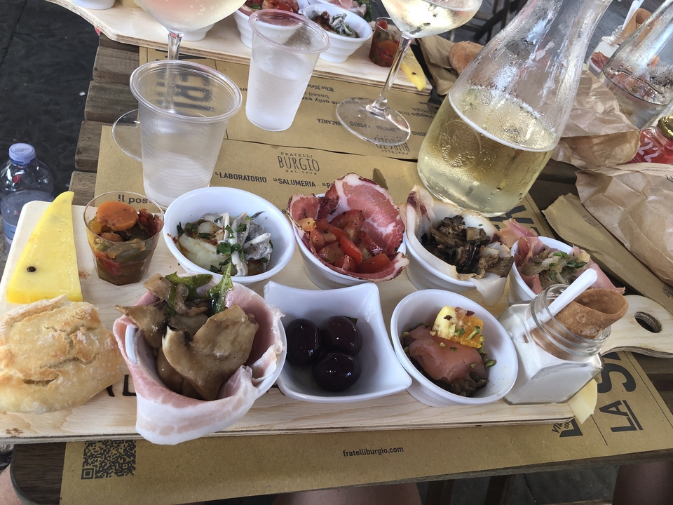 Un assortiment de petits plats et d'amuse-bouches sur une planche en bois, accompagné d'un verre de vin.