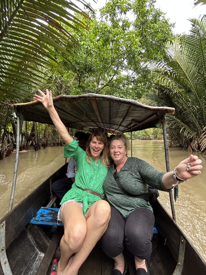 Deux femmes profitant d'une excursion en bateau sur une rivière entourée d'une végétation luxuriante.