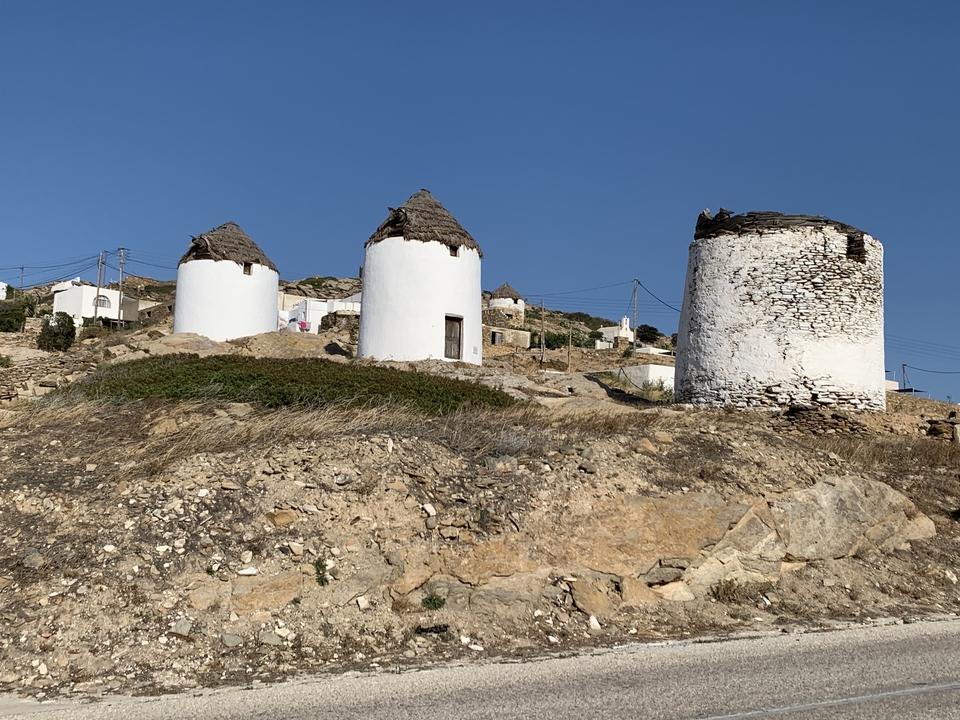 Old windmills on a hilltop with blue sky.