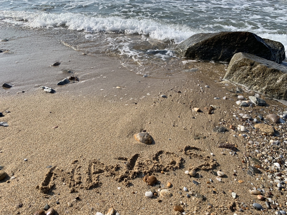 Sandy beach with rocks and the word 'Naxos' written in sand.