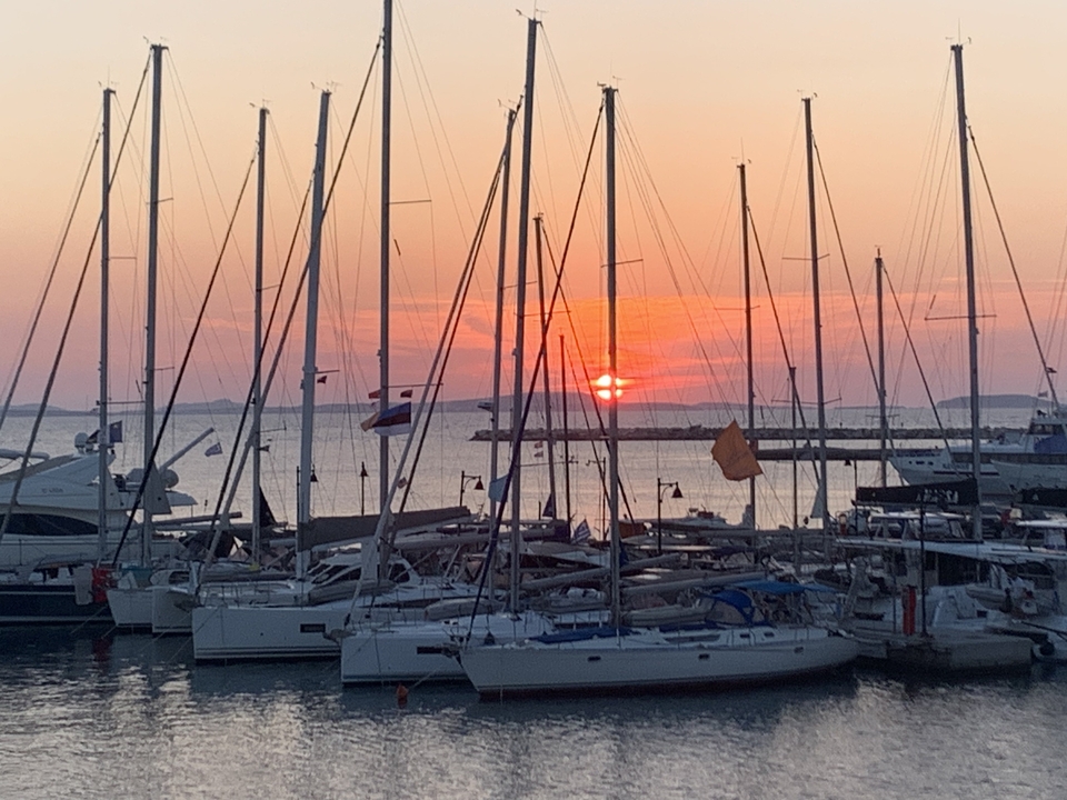 Sunset over a marina with sailing boats.