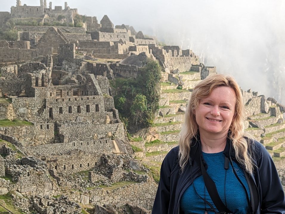 Femme souriante avec les ruines du Machu Picchu en arrière-plan.