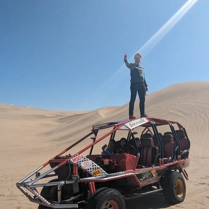 Personne debout sur le toit d'un véhicule tout-terrain dans un paysage désertique.