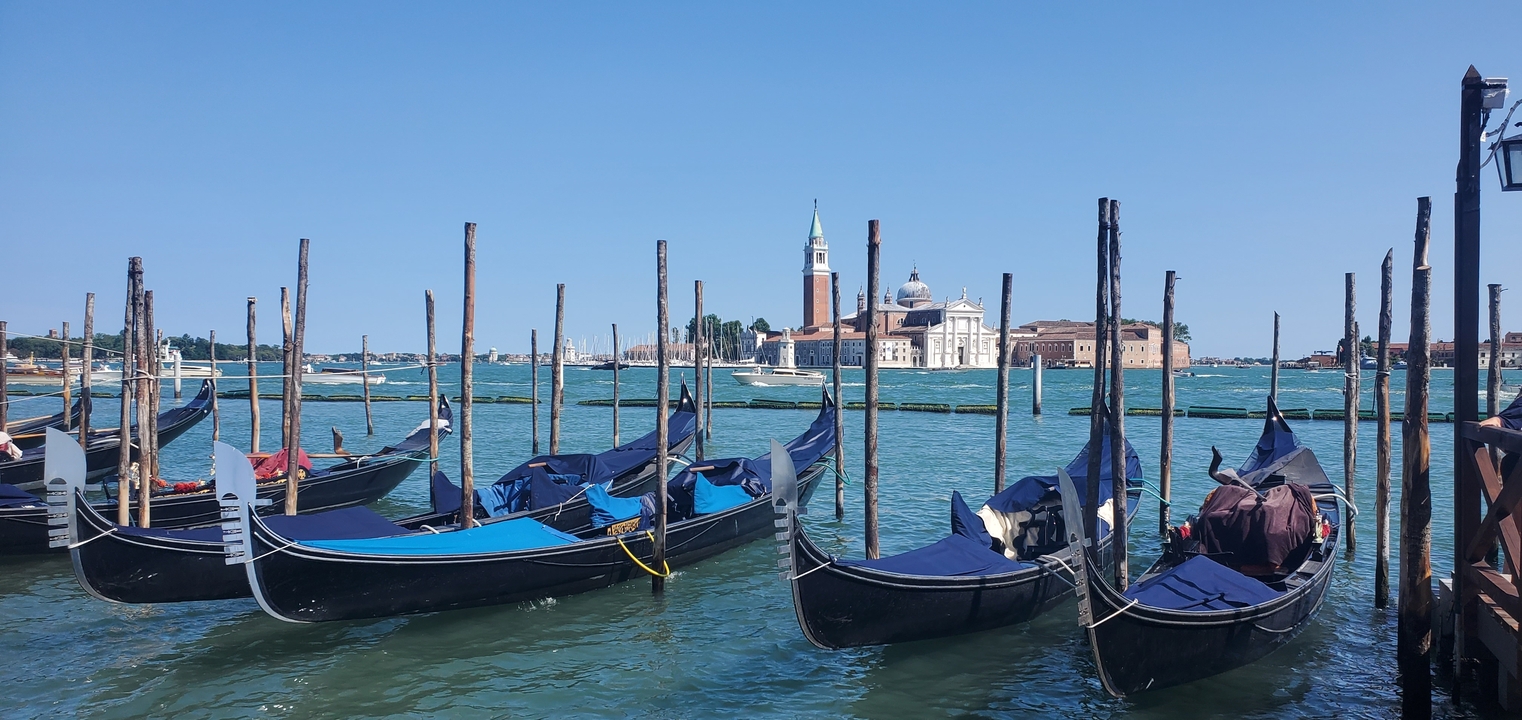 Des gondoles amarrées dans un canal avec une église en arrière-plan.