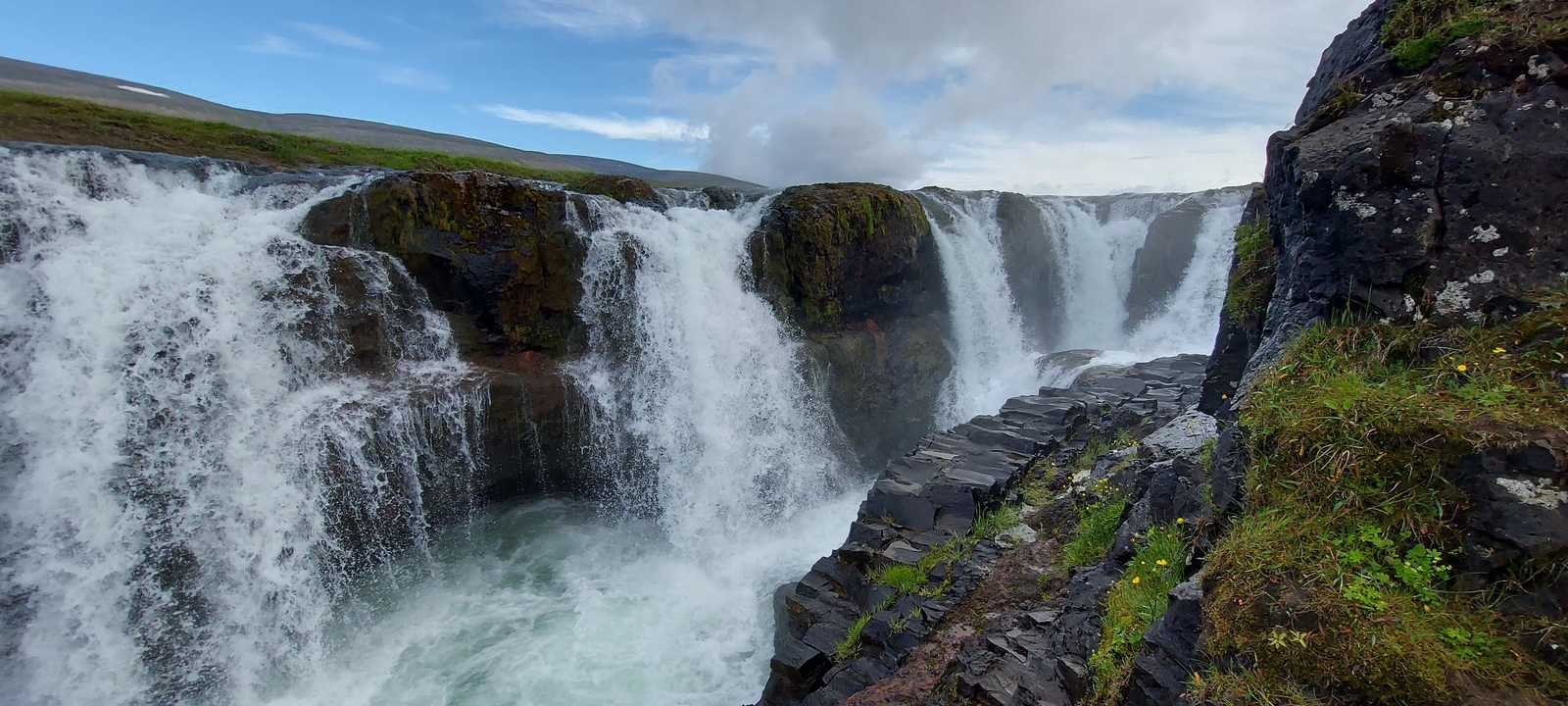 Une cascade qui coule sur des falaises rocheuses.