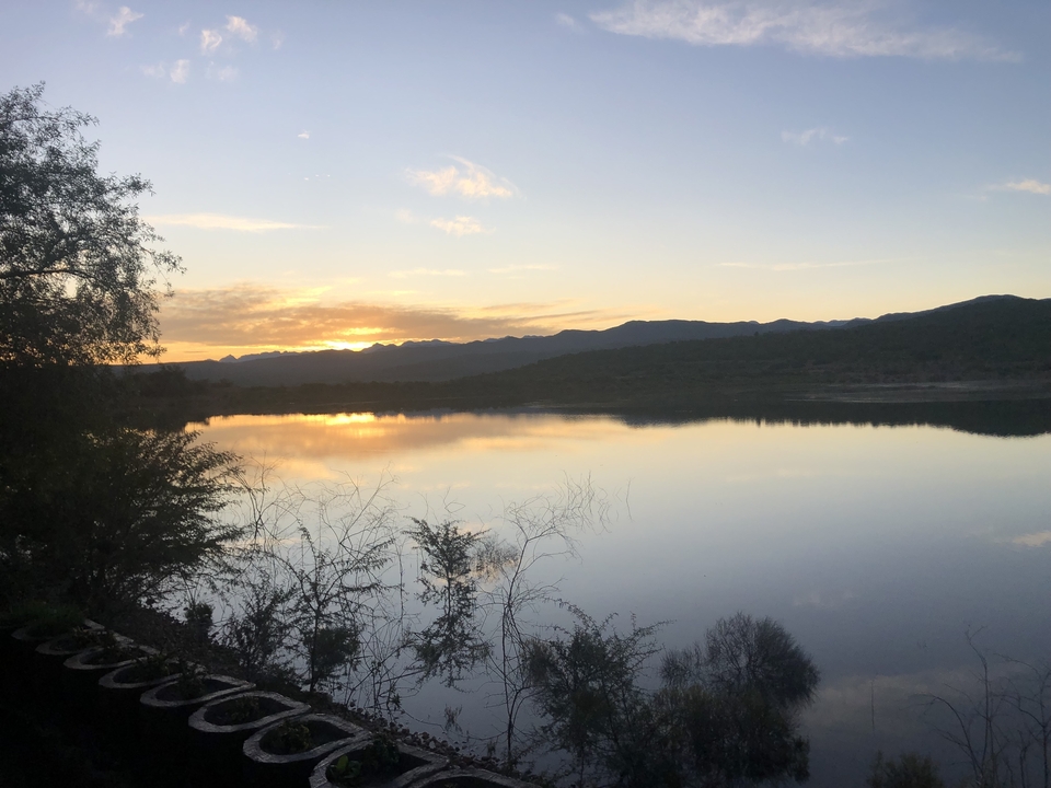 Un magnifique coucher de soleil sur un lac tranquille avec des montagnes en arrière-plan.