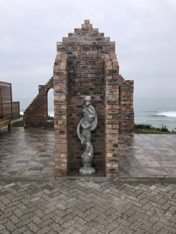 Une structure en brique avec une statue qui surplombe l'océan.