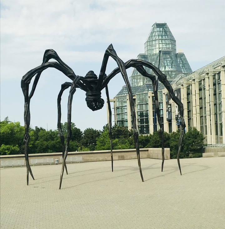 Grande sculpture d'araignée devant un bâtiment moderne.