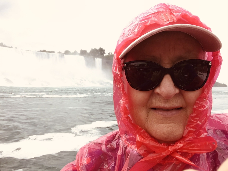 Personne en imperméable rouge devant une cascade.
