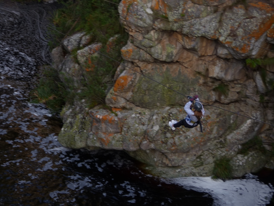 Person ziplining over a rocky gorge.