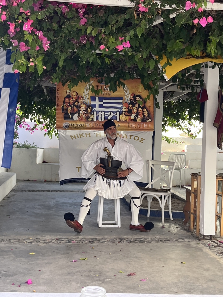 Homme en costume traditionnel assis devant une exposition culturelle.