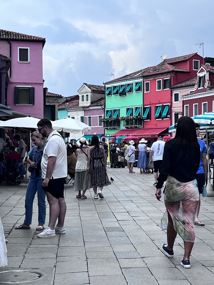 Scène de rue avec des bâtiments colorés et des gens qui marchent.
