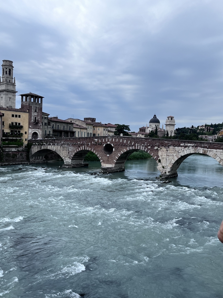 Pont de pierre sur une rivière qui coule avec de l'architecture en arrière-plan.
